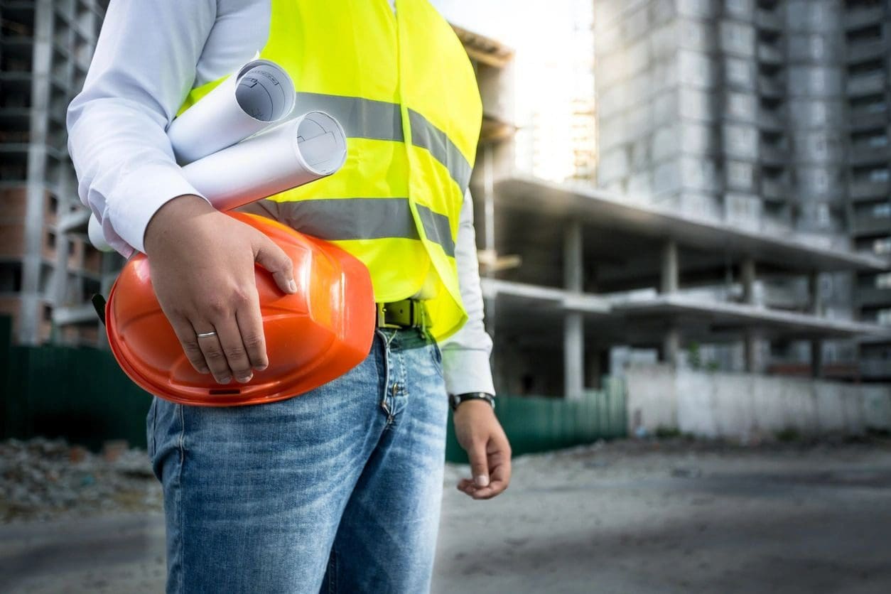 A construction worker holding an orange helmet.